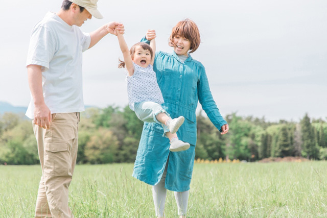 父親と母親と手をつないでジャンプしている女の子