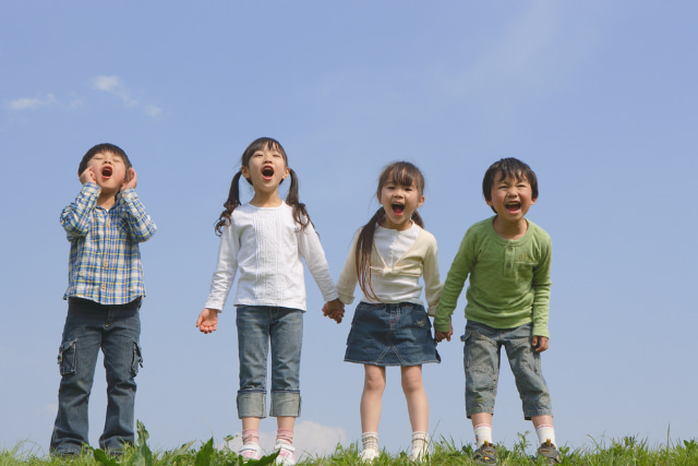 手を繋ぐ子ども3人の子どもと遠くに向かって叫んでいる子ども