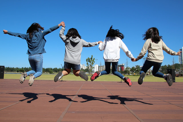 4人の子どもが手をつないでジャンプしている